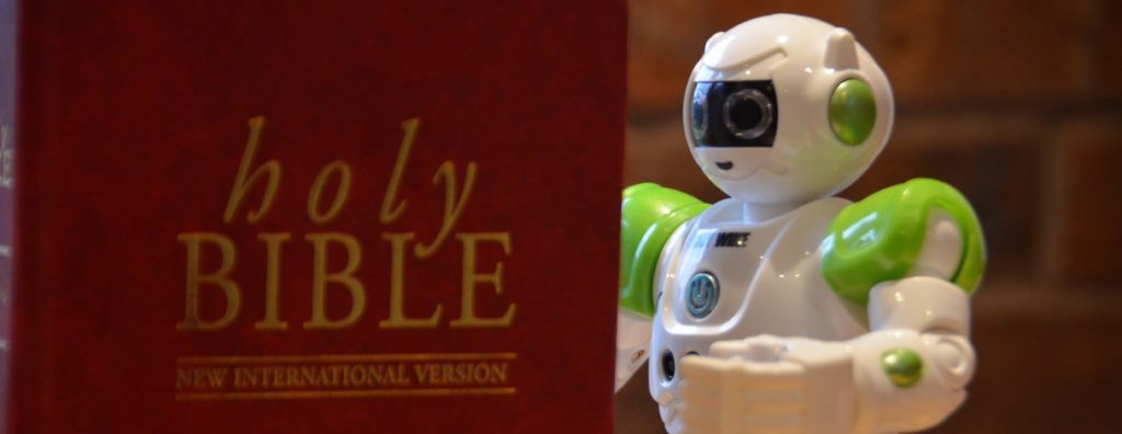 Image of a toy robot "reading" a bible